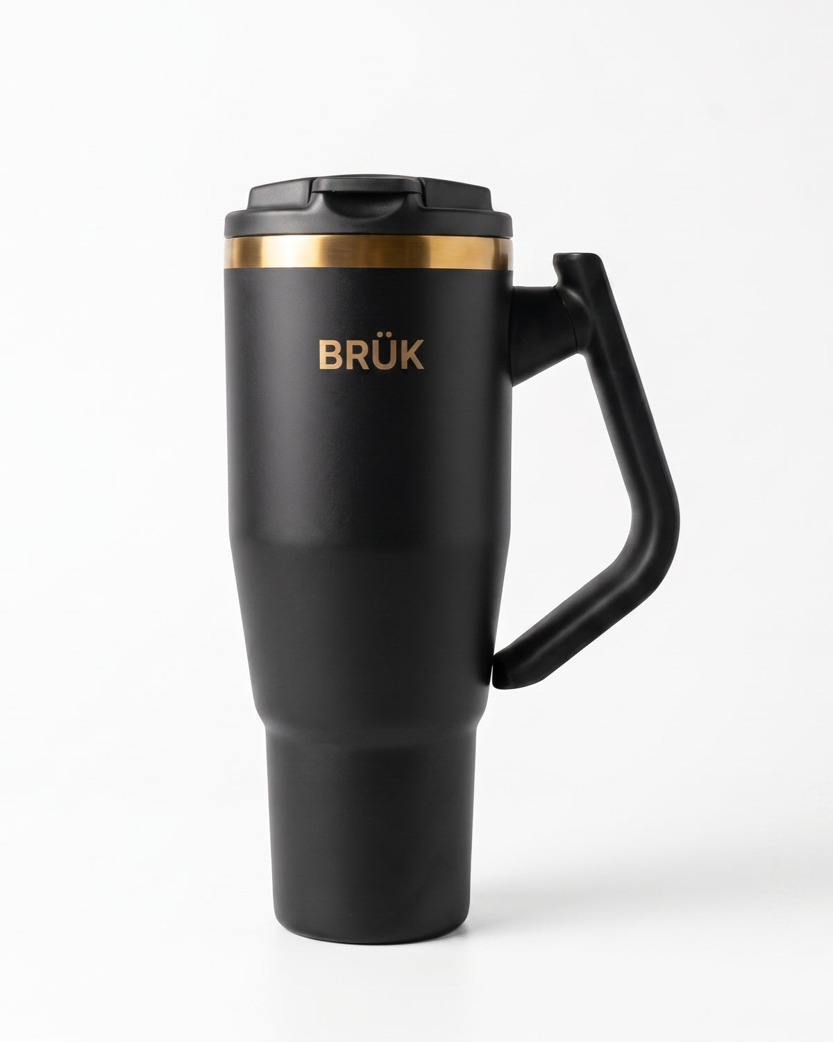 A matte black travel tumbler with a matching black lid and handle, featuring a gold metallic band near the top and the brand name 'BRÜK' in gold lettering, set against a clean white background.